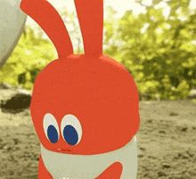 a red and white bunny with blue eyes is standing in the dirt