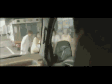 a man in a white coat is talking to a woman in a white dress in front of an ambulance