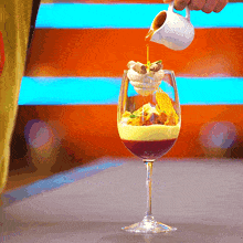 a person pouring liquid into a wine glass with ice cream on top