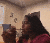 a woman in a red shirt is blowing smoke out of a straw .