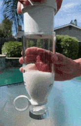 a person is pouring milk into a glass on a table outside