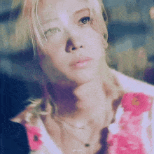 a close up of a woman 's face wearing a pink shirt and necklaces .