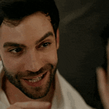 a man with a beard and a white shirt smiles