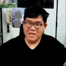 a man with glasses and a black shirt is making a funny face .