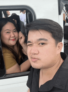 a man is making a funny face while a woman looks out of a window