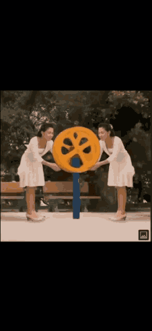 two women are standing next to a yellow wheel