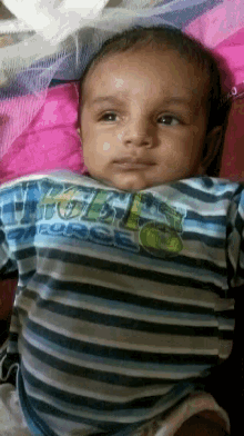 a baby in a striped shirt with a tractor on it