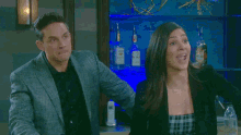 a man in a suit and a woman in a plaid dress are standing next to each other in a bar