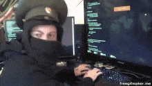 a man wearing a hat and a mask is typing on a keyboard