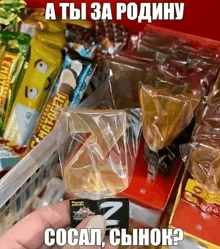 a person is holding a piece of candy in front of a display of candy bars with russian writing on them