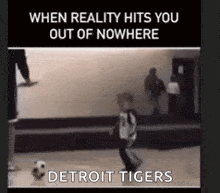 a boy is kicking a soccer ball in front of a sign that says detroit tigers