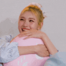 a woman is holding a pink pillow in her arms and laughing .