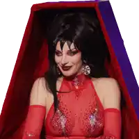 a woman in a red dress and black hair is sitting in a coffin