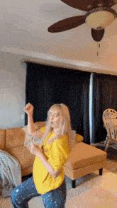 a woman is dancing in a living room with a ceiling fan