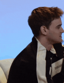a young man wearing a black and white jacket with the word essential on the side