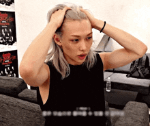 a man with long blonde hair is holding his head with his hands