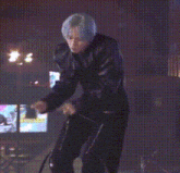 a man with blue hair is riding an exercise bike at night