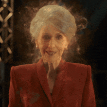 a woman in a red jacket is smiling with smoke coming out of her face
