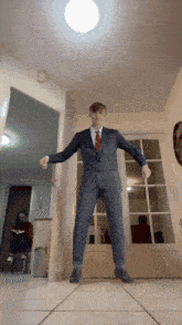 a man in a suit is dancing in a hallway