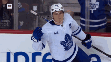 a toronto maple leafs hockey player is holding a stick