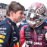 a man wearing a helmet that says petronas stands next to another man