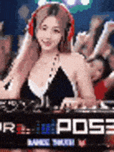 a woman is wearing headphones and playing a dj set in front of a crowd .