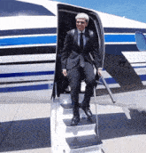 a man in a suit climbs the stairs of an airplane