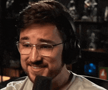 a man with glasses and headphones is smiling into a microphone