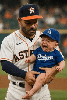 a man holding a baby wearing a dodgers shirt
