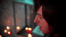 a close up of a person 's face with candles behind them