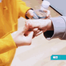 a person in a yellow shirt is holding a bottle of water in their hand