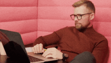 a man wearing glasses is sitting in front of a laptop