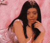 a woman in a pink satin dress is laying on a bed .