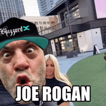 a man wearing a blizzard hat stands in front of a woman and says joe rogan