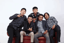 a group of young men are posing for a picture while sitting on a couch