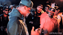 a gif from gifrun.com shows a man wearing a hat and a hoodie