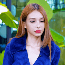 a woman with red lips is wearing a blue sweater with a fur collar