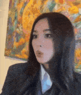 a close up of a woman wearing a suit and tie in front of a painting .