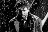 a man in a suit and tie is standing in the rain .