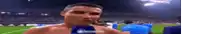 a man without a shirt is taking a selfie on a soccer field with a microphone .