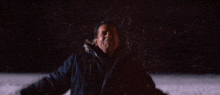 a man is holding a torch in the dark while standing in the snow .