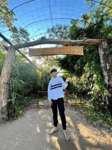a man stands in front of a wooden sign that says ' tb ' on it