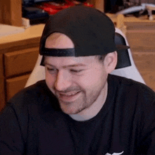 a man wearing a black hat and a black shirt is smiling .