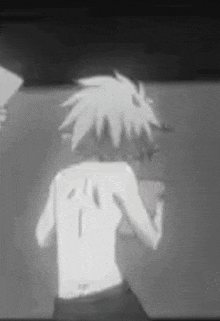 a black and white photo of a person with a tattoo on their back standing in front of a wall .
