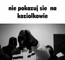 a black and white photo of a group of people with the words nie pokazuj sie na koziołkowie