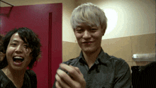 two men are laughing in front of a pink door with the number 0 on the wall