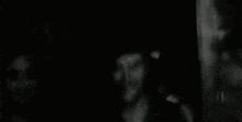 a black and white photo of a man smoking a cigarette in a dark room .
