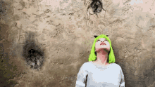 a woman with green hair is looking up at a wall
