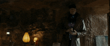 a man standing in a dark room with a lamp in the background