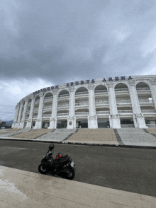 a motorcycle is parked in front of a large building that says sports arena